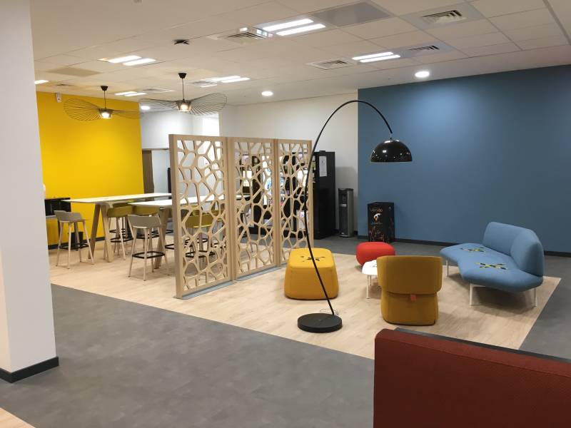 Aménagement cafétéria et espaces collaboratifs chez EKIUM Lyon avec canapé lounge